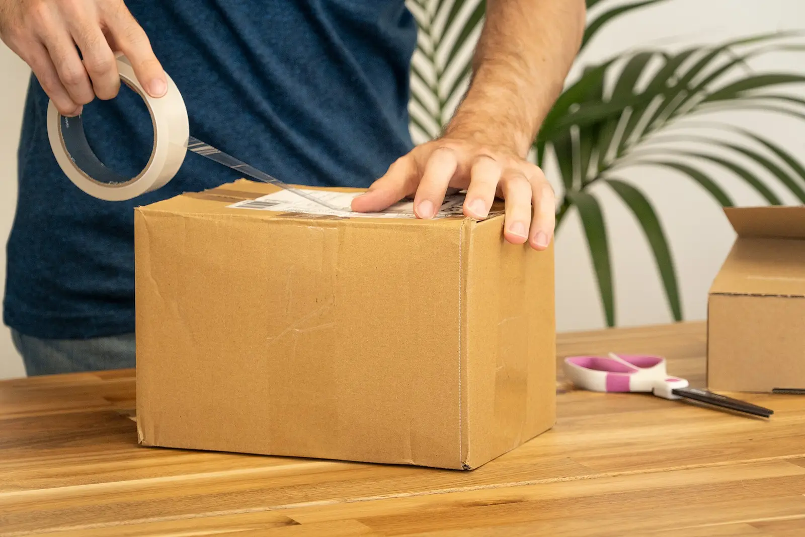段ボール箱にテープを貼って荷物を送る準備をしているところ